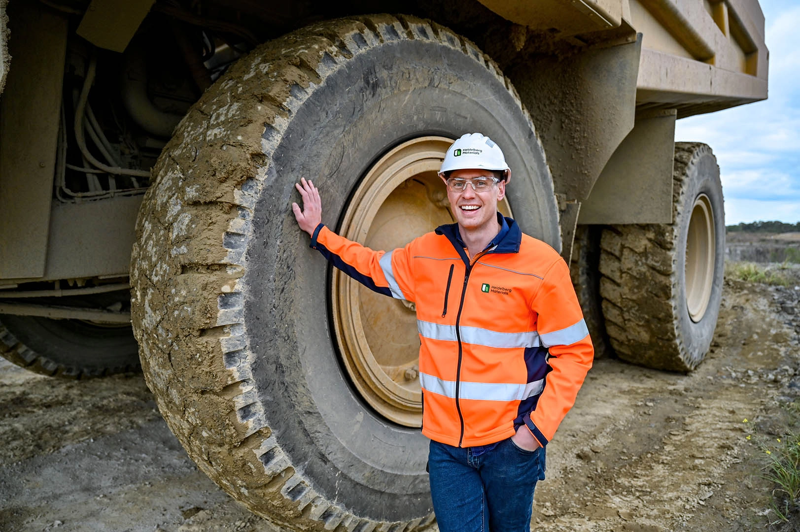 Team member with helmet and safety vest in front of truck tire