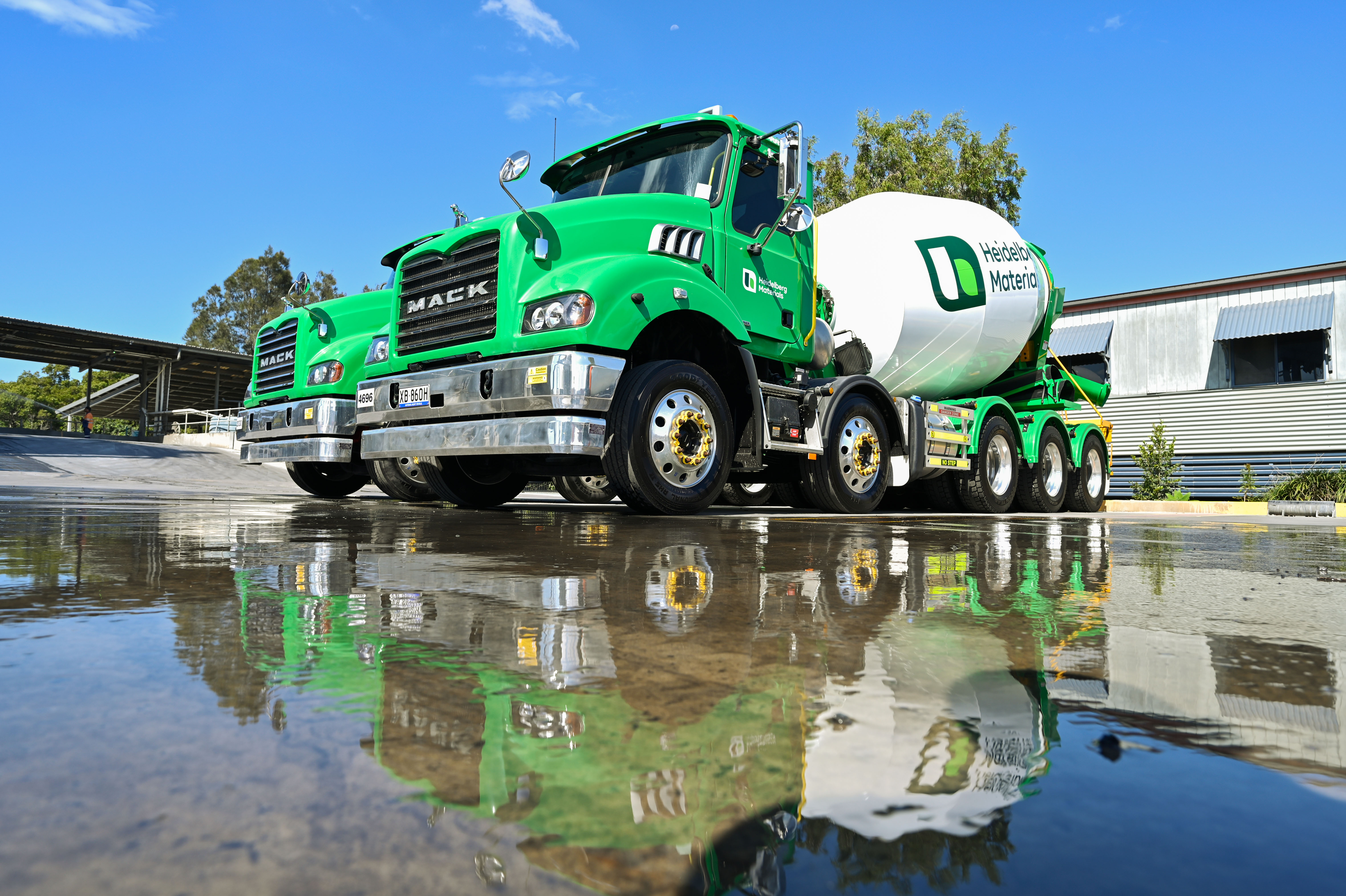 Heidelberg Materials green cement trucks onsite near batching facility with clear sky