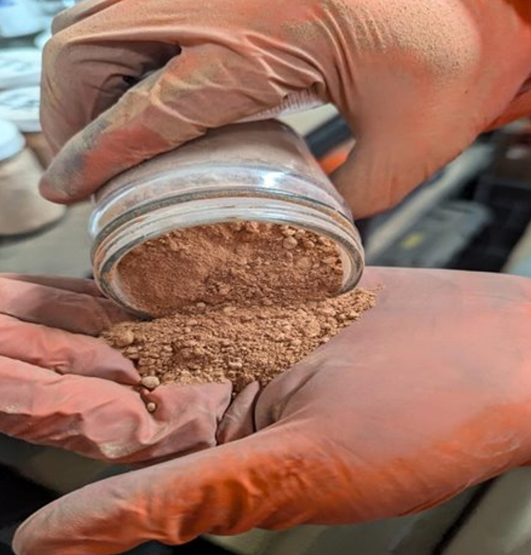 Hands holding a sample of raw clay material