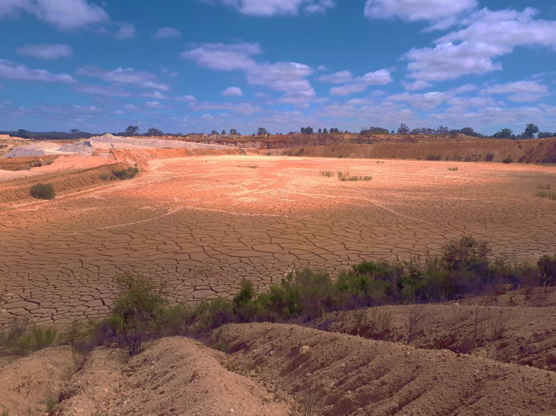 Desert landscape with exposed clay terrain under a blue sky