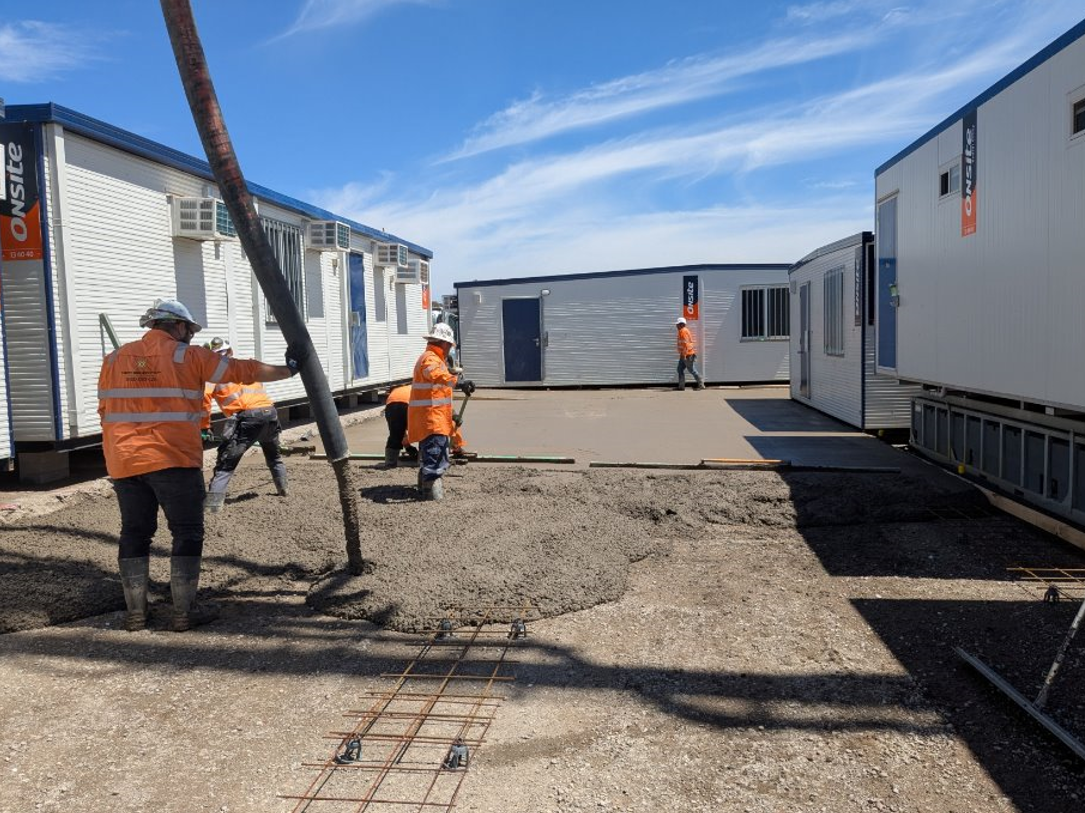 Concrete being poured over a clay base at a construction site