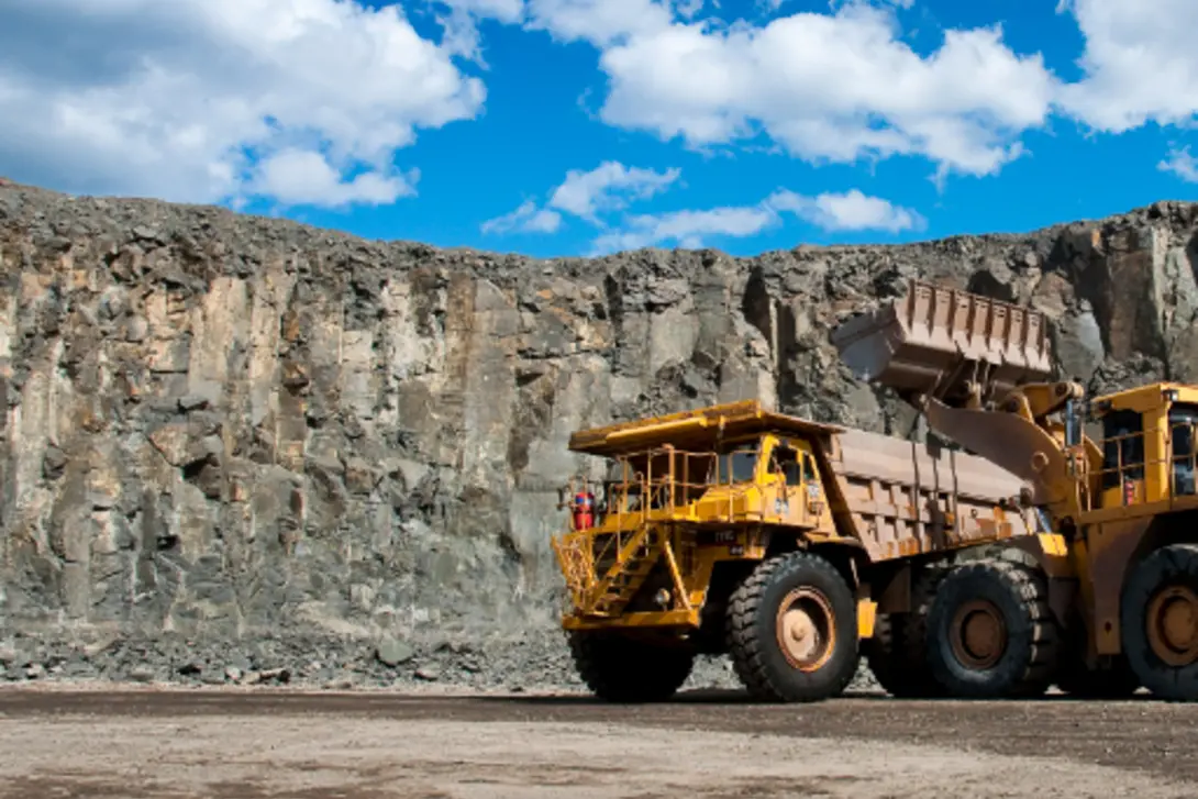 Heavy dump truck being loaded with crushed rock by a loader in a quarry, supporting large-scale construction and infrastructure projects.