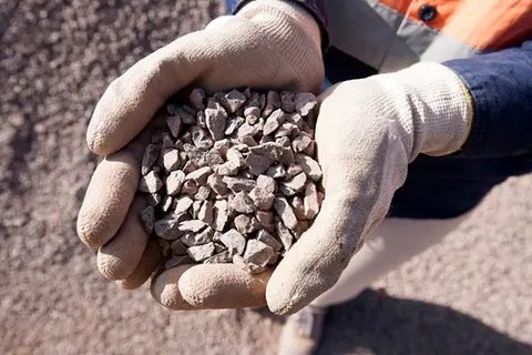 Worker holding engineered fill material made of graded crushed rock, used for compaction, backfilling and ground stabilisation in construction projects.