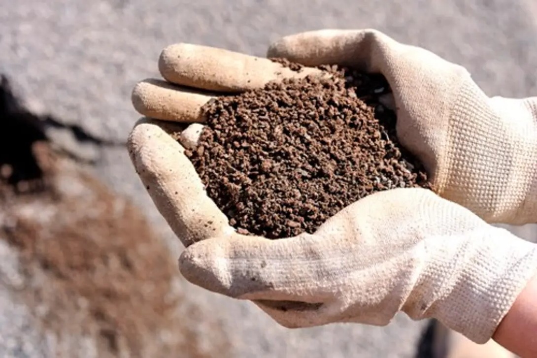 Close-up of fine slab fill material in hand, showing well-graded small aggregates used for levelling and preparing a stable base before concrete slab installation.