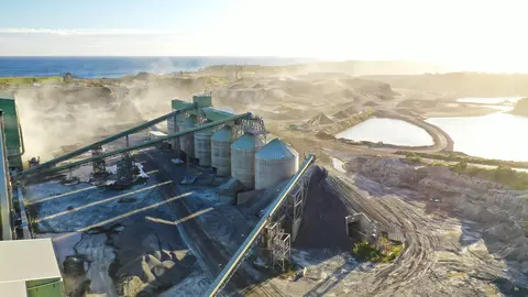 Aerial view of Heidelberg Materials Australia’s Kayasand plant featuring processing infrastructure, stockpiles and surrounding quarry landscape beside the coastline during sunrise.