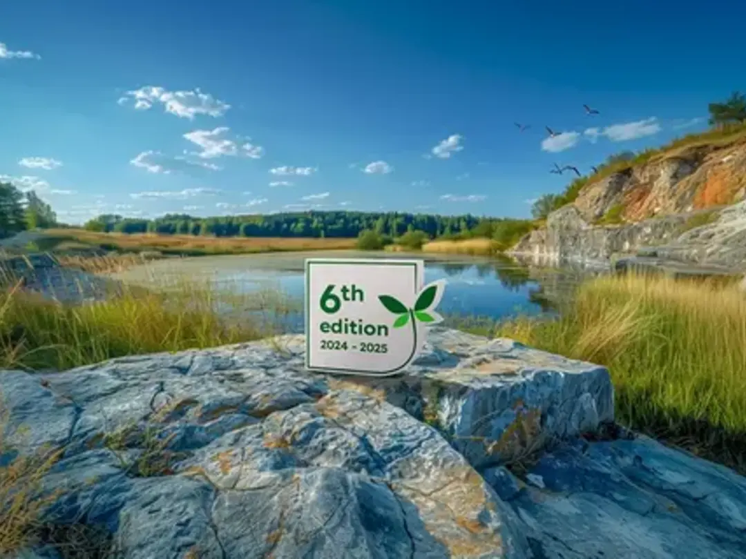 Quarry Life Award 6th edition sign on rock overlooking a rehabilitated quarry lake with greenery and blue sky
